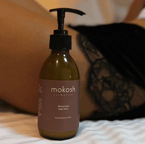Lubrifikues i trupit MOKOSH me aromë Sandalwood dhe Amber për hidratim dhe ndriçim të lëkurës.